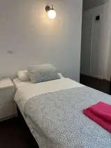 Cama individual vista de lado con mesilla a la izquierda y pasillo al fondo en la Habitación Doble Confort